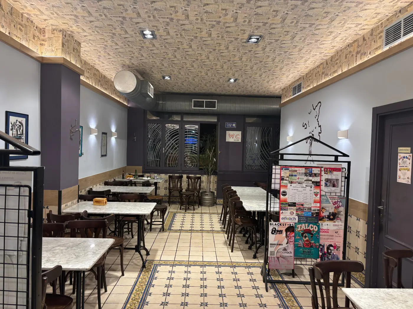 Comedor de El Viejo Roble: mesas de mármol, baldosa hidráulica y zócalo berenjena